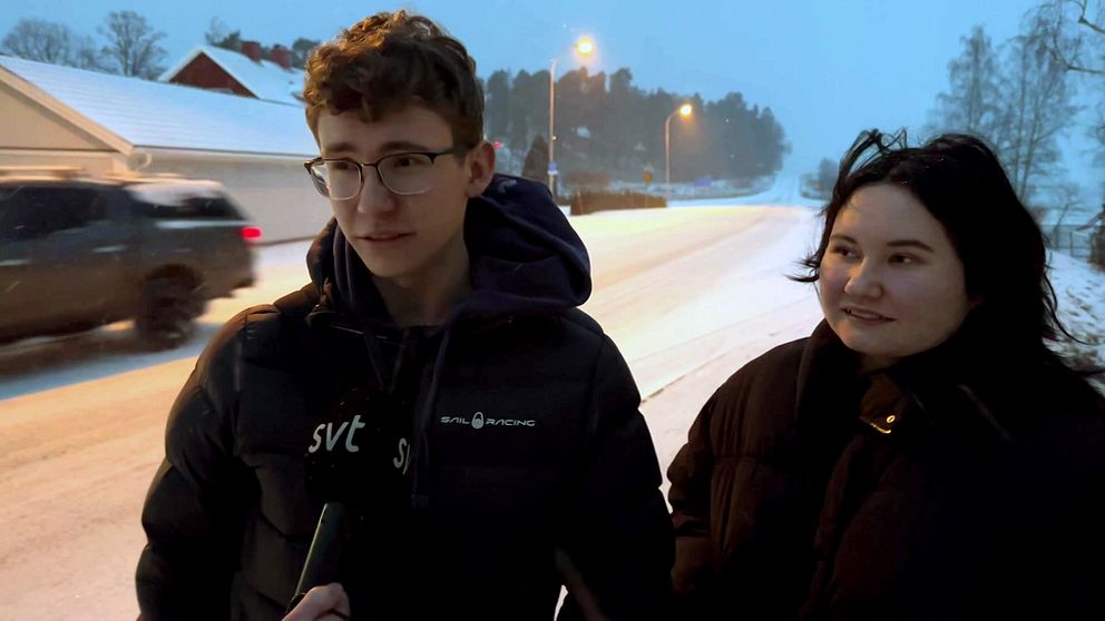 Två ungdomar vid en väg i snön