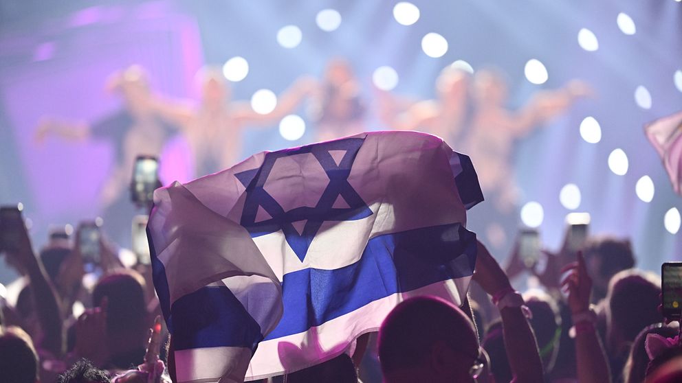 Israeliska flaggan i ett publikhav framför en scen
