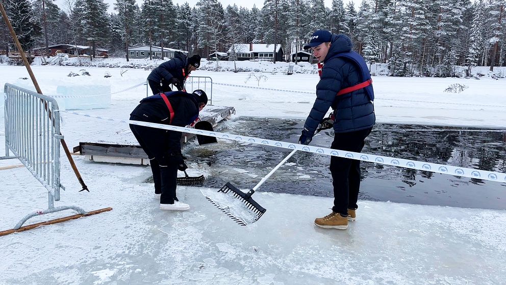 tre personer skottar upp is vid en frusen sjö