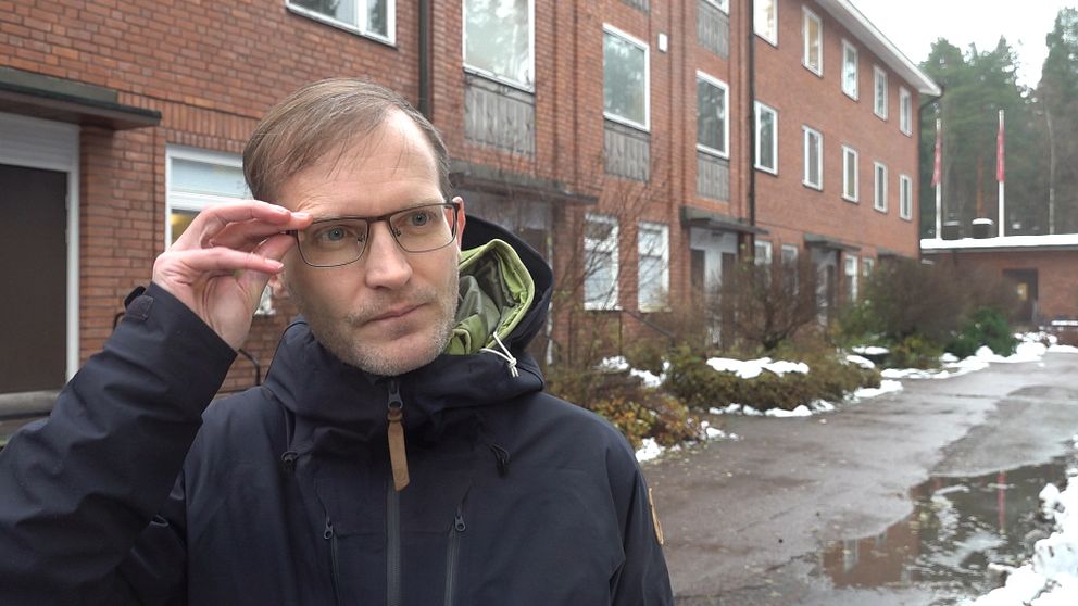 Smittskyddsläkaren Fredrik Rücker står utanför infektionskliniken i Falun, iklädd regnjacka och glasögon.