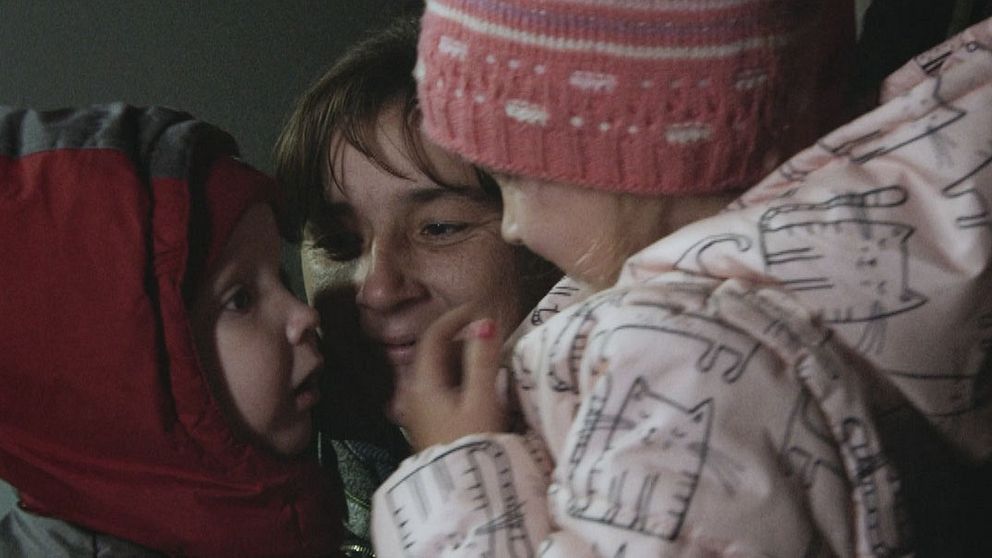 Viktor med röd luva återförenas med sin mamma och syster som ler