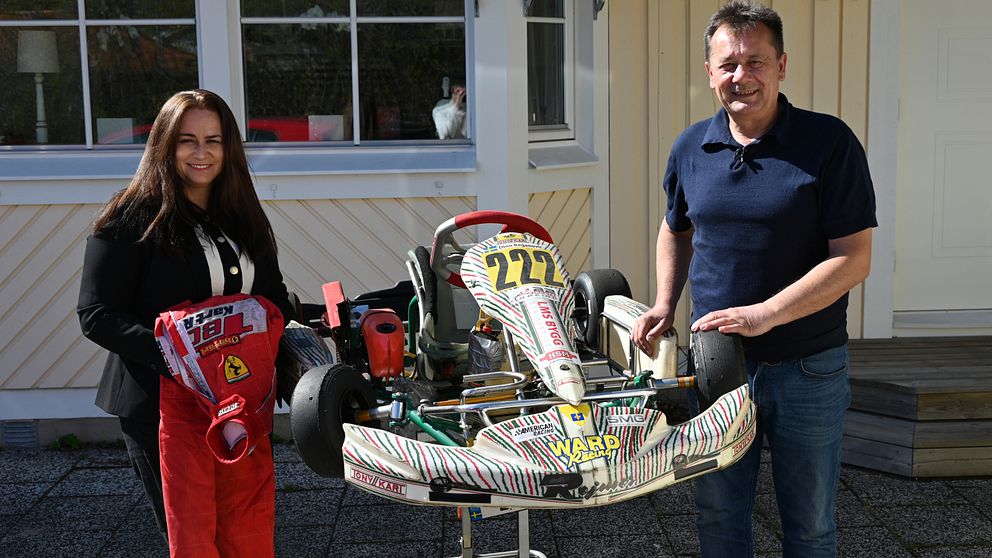 Två personer står bredvid en gokart utomhus framför ett hus.