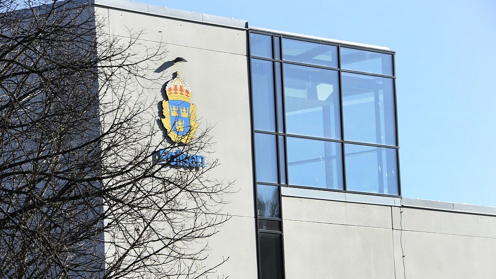 en grå byggnad med glasfönster och en polislogga