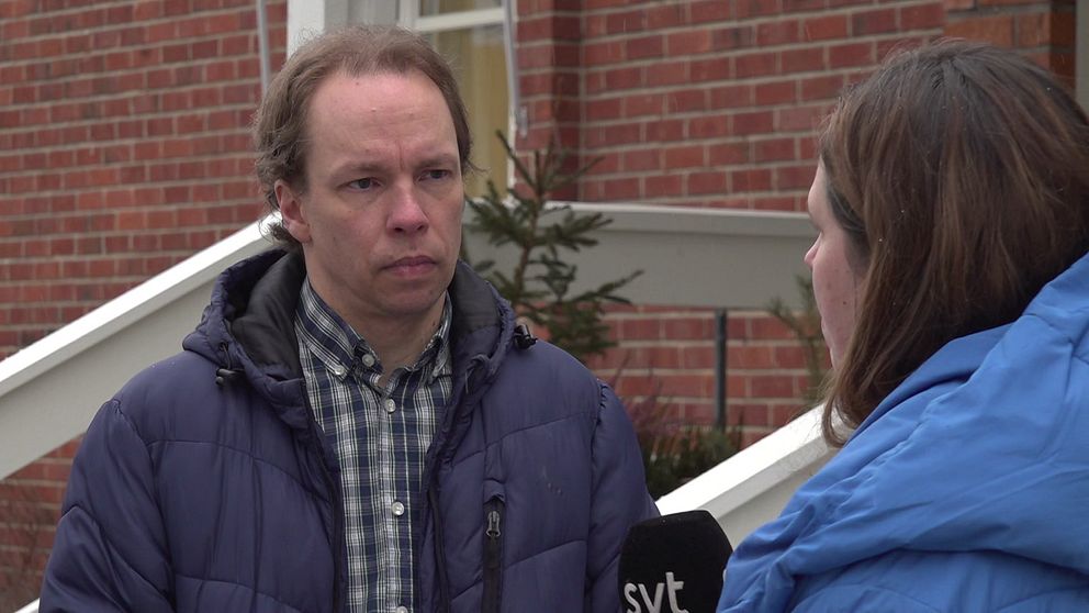 Reporter från SVT intervjuar person utanför tegelbyggnad.