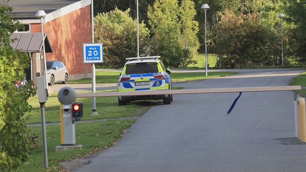 En polisbil står bortom en nedfälld bom.