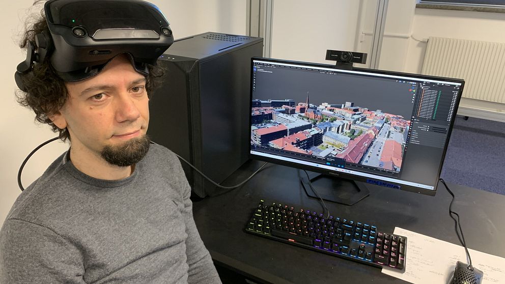 Man med VR-glasögon framför en dator