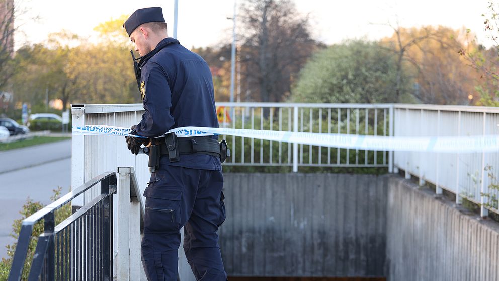 Polis sätter upp avspärrningsband vid en gångtunnel under en bro.