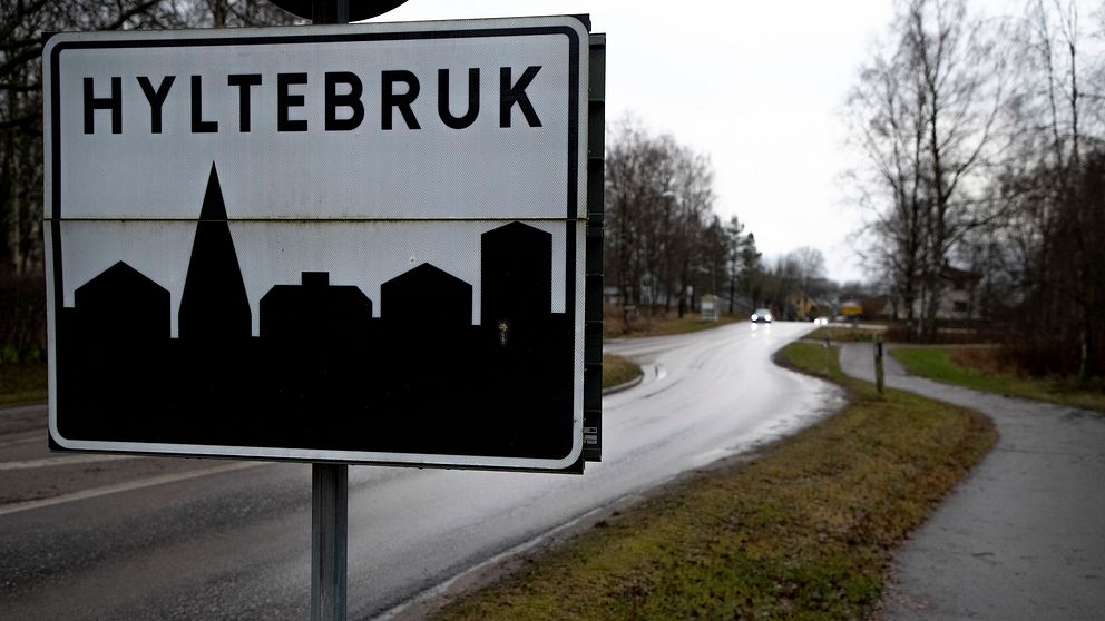 Vägskylt vid infart till Hyltebruk, omgivning med väg och träd.