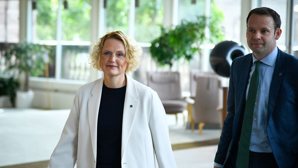 Två personer i formella kläder går tillsammans inomhus.