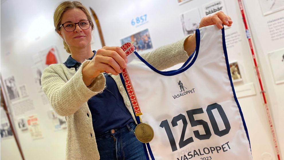 Vasaloppets pressansvarige Camilla Sany Swarén håller upp en nummerlapp och en medalj.