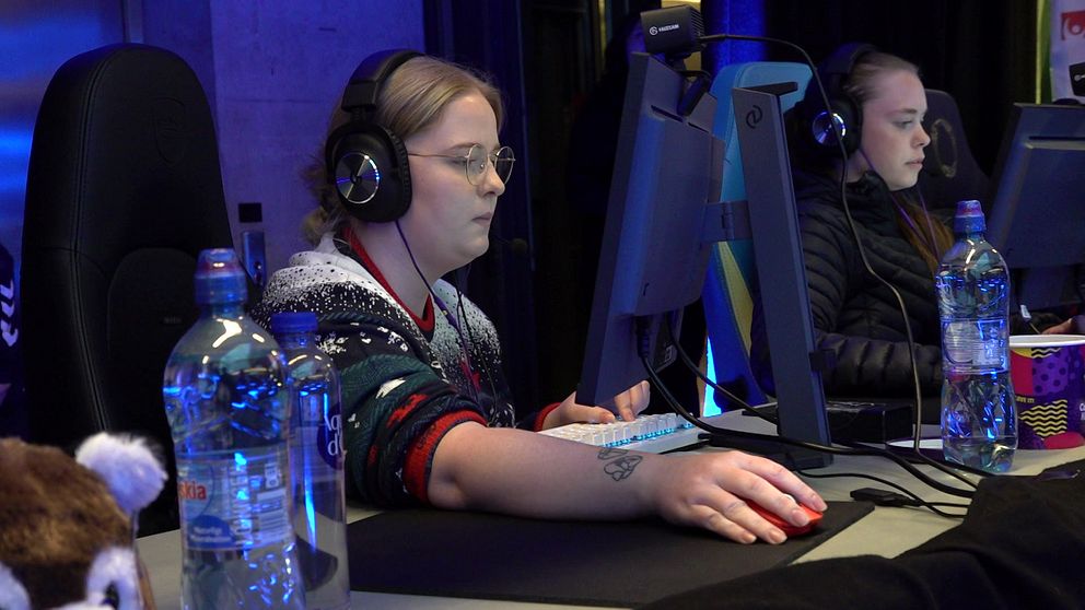 Två kvinnor gejmar sitter framför dator.