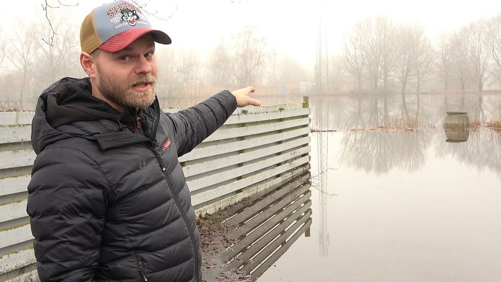 Joost Sjöström-Tiddens pekar på en äng som är översvämmad med vatten i Revingeby.