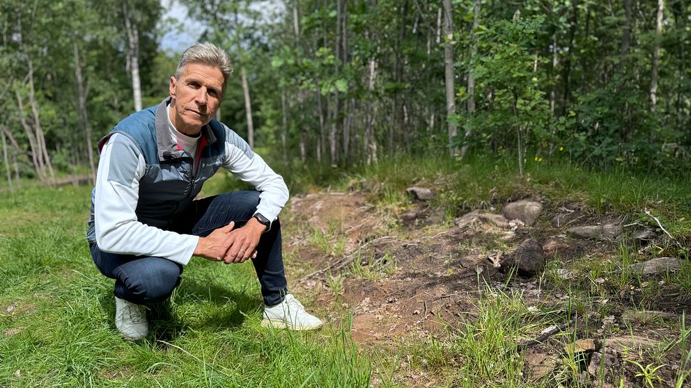 Johan Arvidsson sitter vid en skadad fornlämning.
