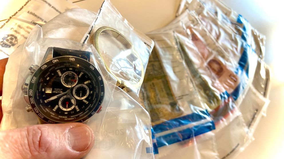 Stöldgods i form av Klocka och sedelbuntar i plastpåsar på bordet, hos polisen.