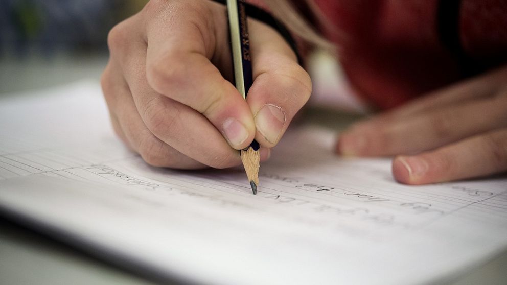 En bild på en hand som håller i en penna och skriver på ett papper.