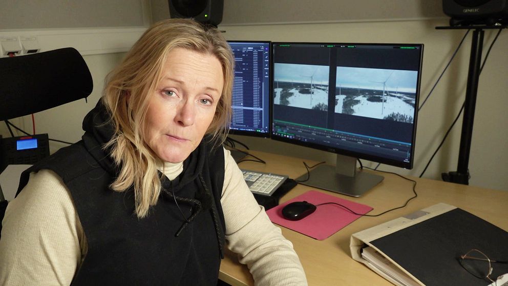 SVT:s reporter Randi Gitz sitter framför dataskärmar med bilder från vindkraftspark