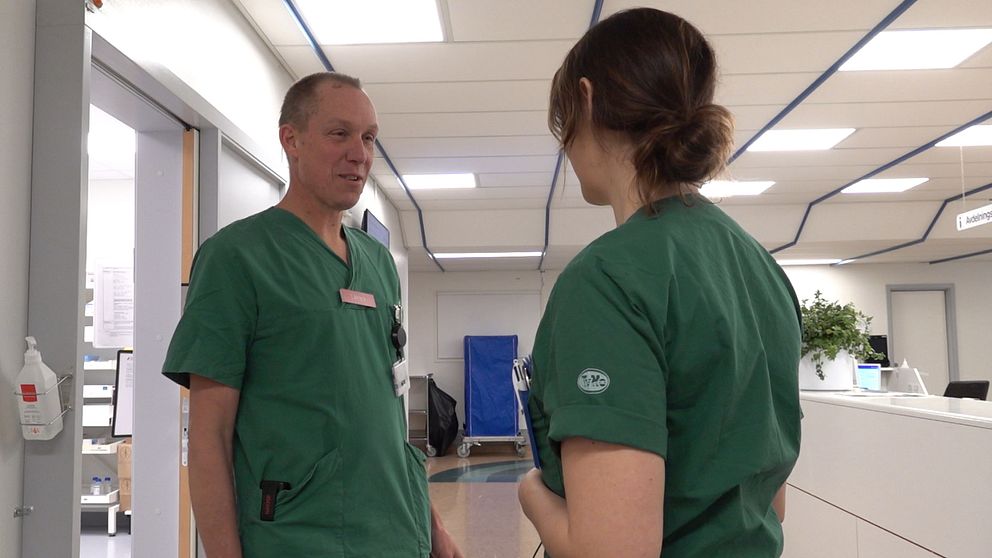 En manlig läkare och en kvinnlig sjuksköterska pratar med varandra.