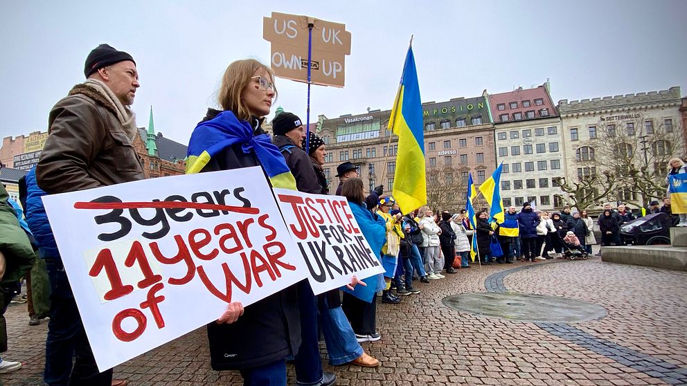 Demonstranter med ukrainska flaggor håller plakat om 11 år av krig.