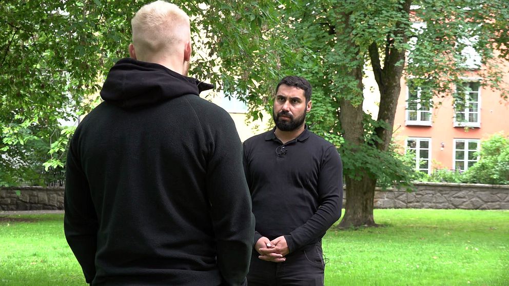 Anonym nlond man med svart hoodie står med ryggen mot kameran