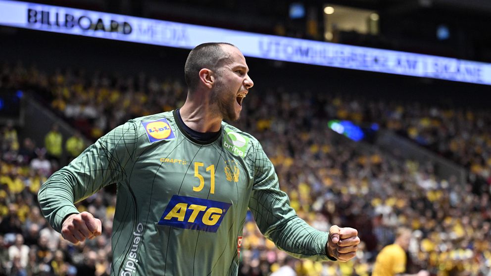 En handbollsmålvakt i grön tröja firar ett mål eller en räddning under en match, med en stor publik i bakgrunden.