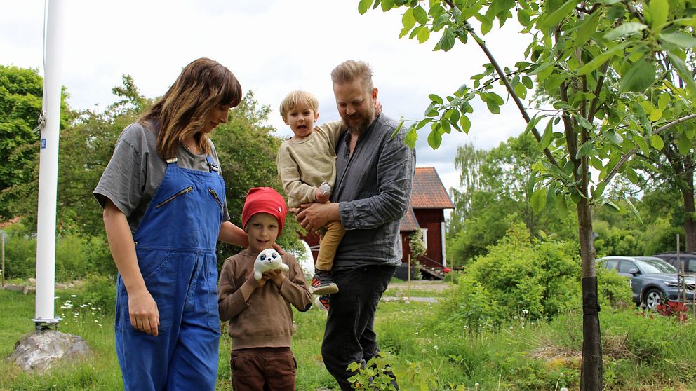 Två föräldrar och två barn i en trädgård.