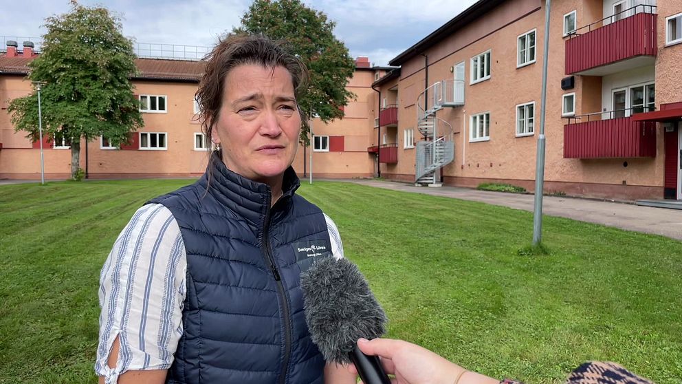 Jenny Brindbergs, lokal ordförande Sveriges lärare i Malung-Sälens kommun, står på en gräsmatta framför ett flerfamiljshus.