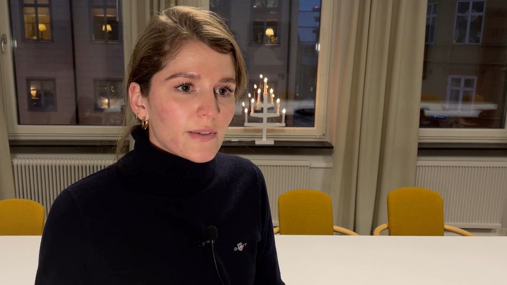 En kvinna med svart polotröja och mörkt hår; bakom henne står gula stolar och en adventsljusstake i ett kontorsrum på Länsstyrelsen Dalarna..