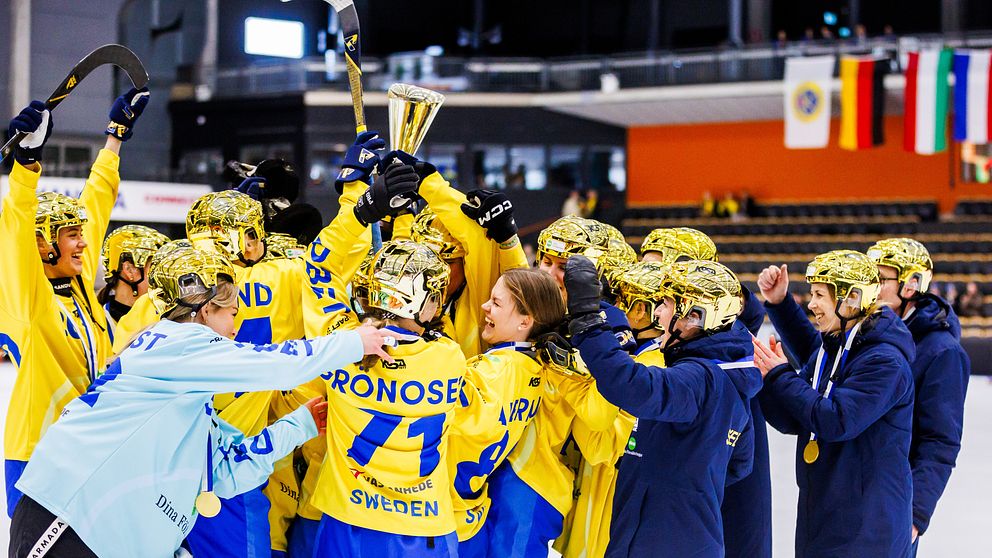 Svenska bandylag firar med pokal på isen, omgivna av glada lagkamrater.