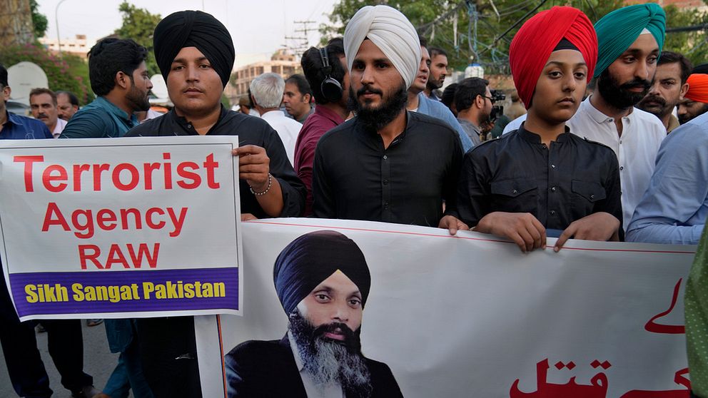 Män med turban håller upp en banderoll med ett porträtt av den mördade sikhledaren Hardeep Singh Nijjar.