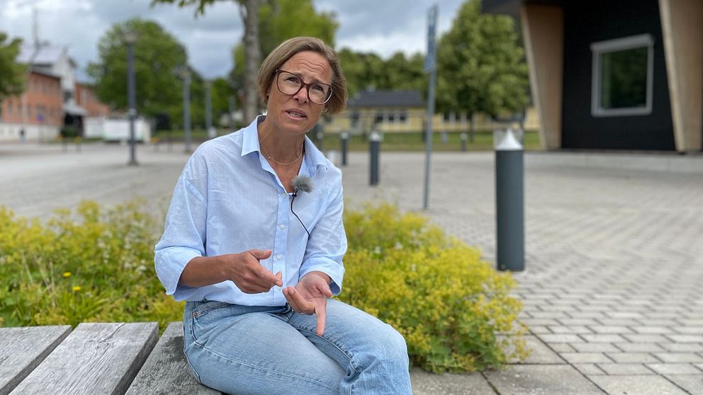 En kvinna sitter på en bänk och berättar.
