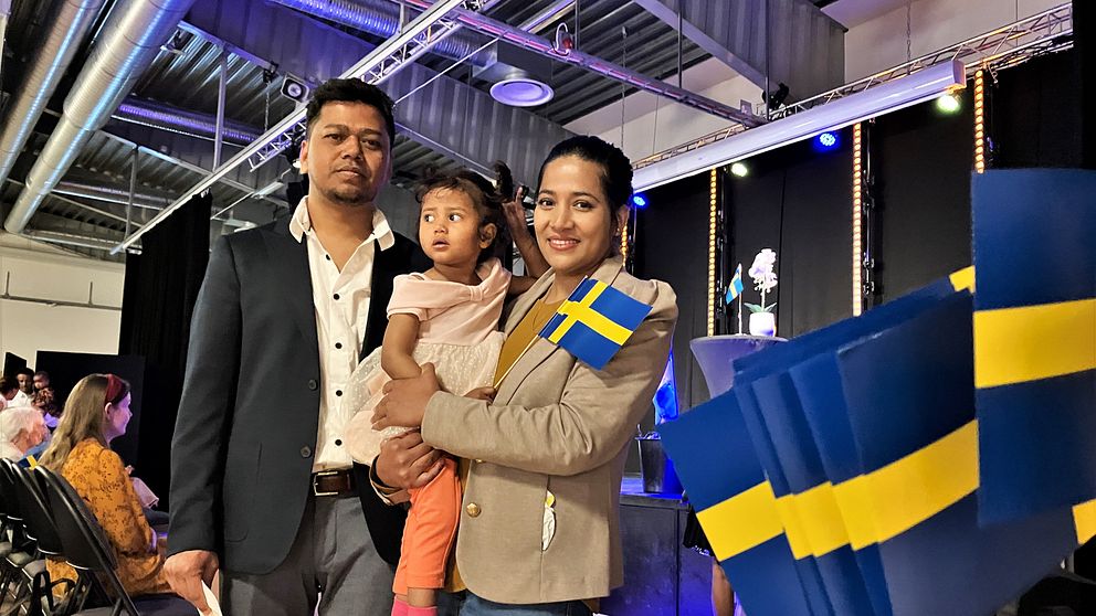 Familjen Barua står framför en scen i Tierp med svenska flaggor bredvid sig