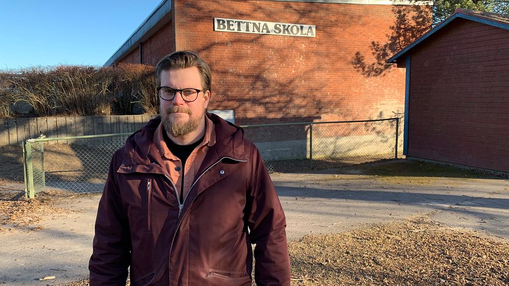 Man med skägg och glasögon står framför Bettna skola och tittar in i kameran