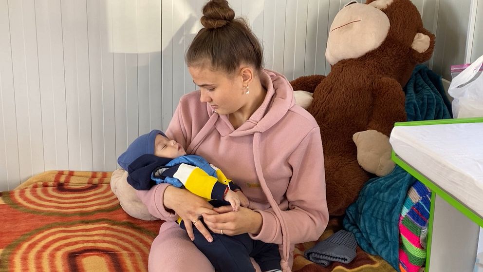 Ukrainska mamman Andreea tittar på sonen Denis som ligger och sover i hennes famn. Bilden är tagen i Hoppets stjärnas barack vid gränsstationen Siret mellan Ukraina och Rumänien