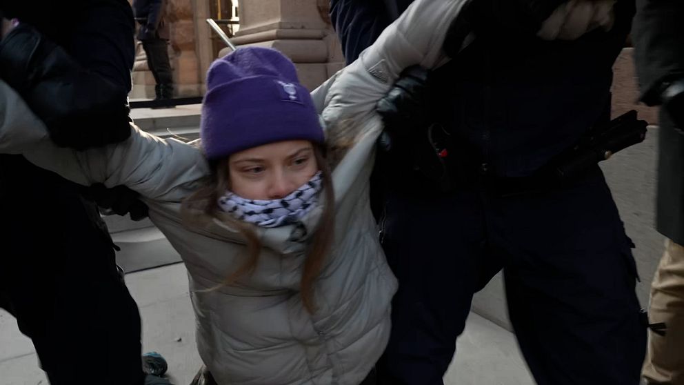 Greta Thunberg lyfts bort av två poliser.