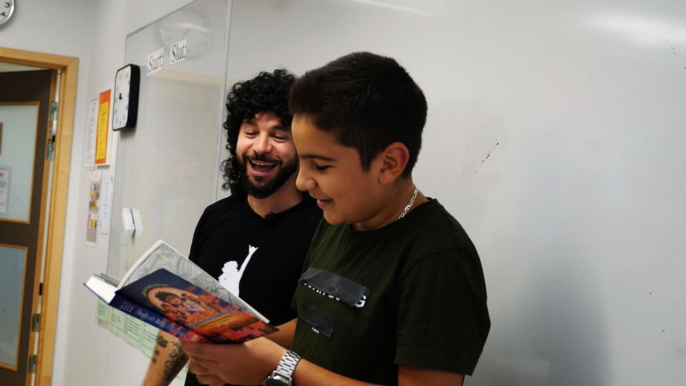 ”Lilla Al-Fadji” kikar över axeln på elev som läser ur hans bok