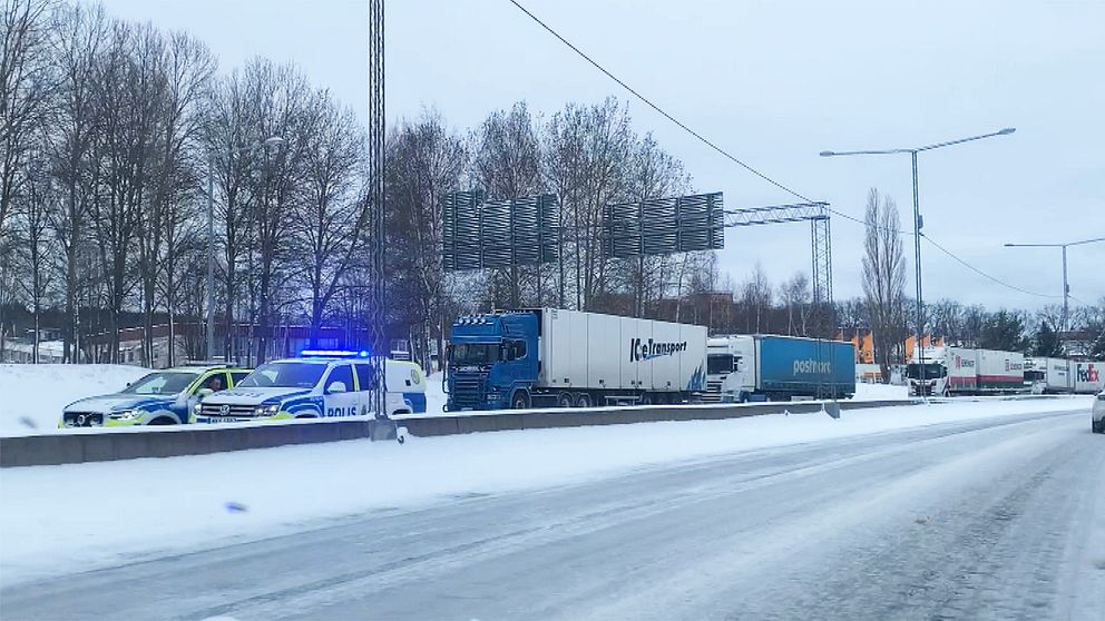 Köer av lastbilar. Längst fram i kön står två polisbilar.