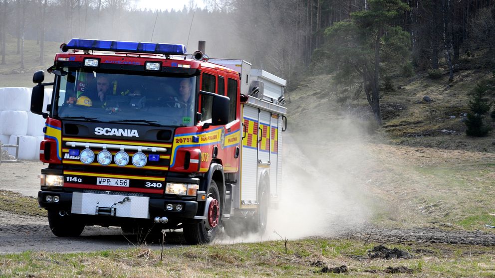 Brandbil på en åker och rök från en mindre gräsbrand.