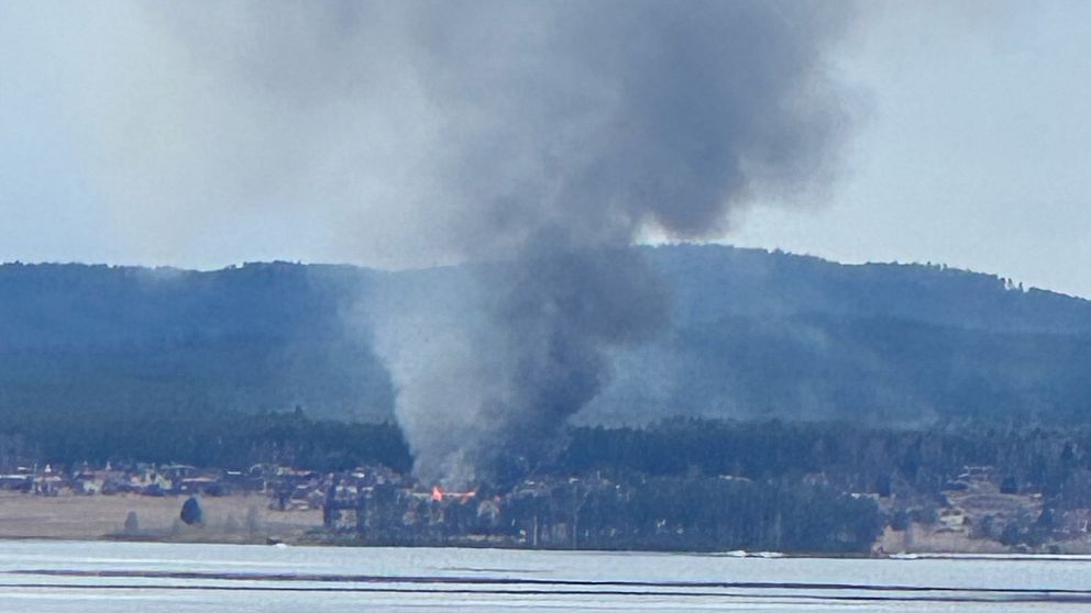 Stort rökmoln från en brand på andra sidan av en sjö