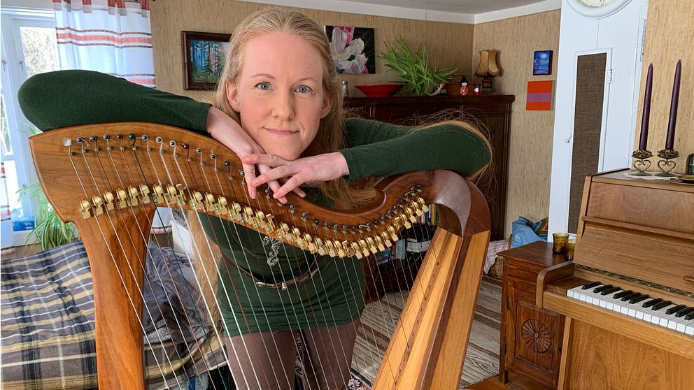Mia Westlund står lutad över sin harpa