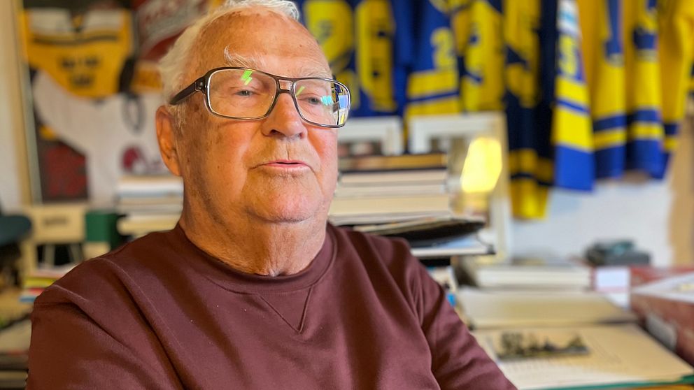 Hasse Andersson på sitt kontor omgiven av sina hockeytröjor.