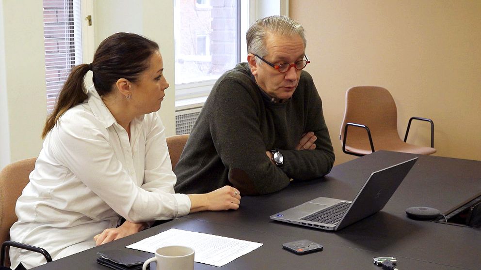 Två personer diskuterar vid ett bord med en laptop och dokument.