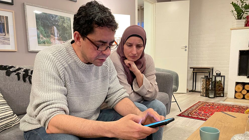Walid Hams från Strövelstorp sitter i sitt hem med en telefon i handen. Bredvid honom sitter hans fru.