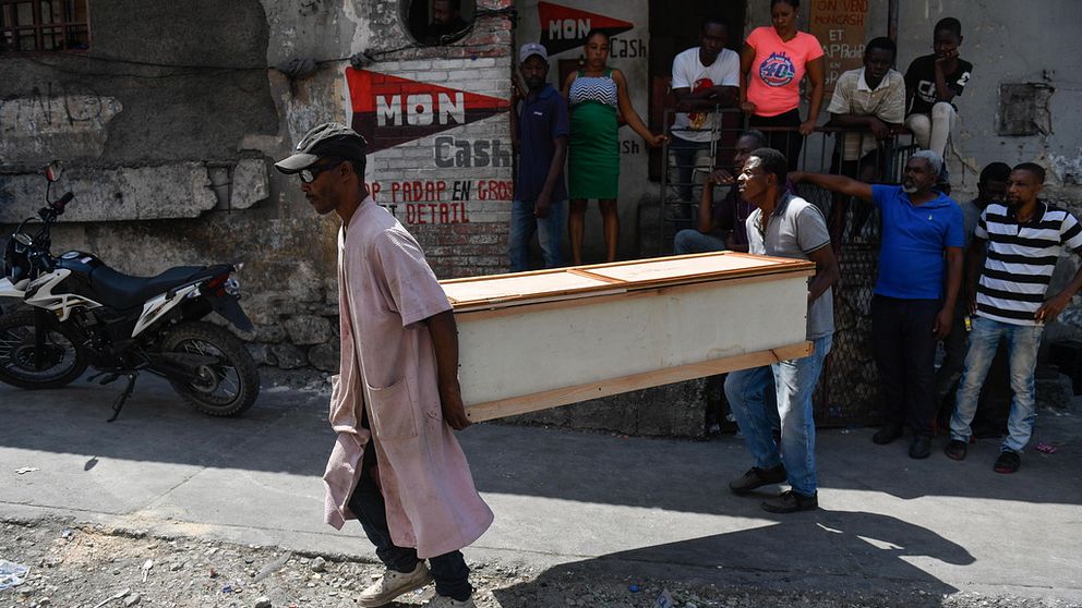 Två personer bär en kista i Port au Prince i Haiti.