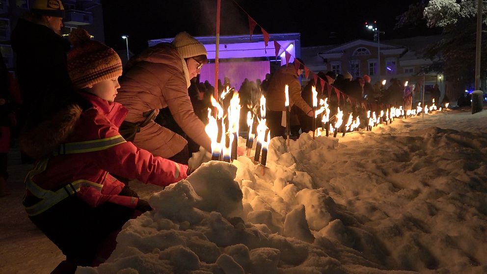 Manifestation för mördade Tintin i Luleå, människor som lämnar ifrån sig sina facklor i snön.