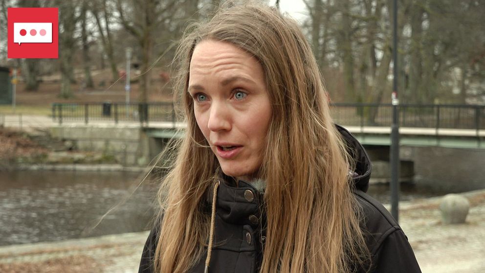 Person med långt, blont hår står vid en kanal med en bro i bakgrunden. Storstadsmiljö.