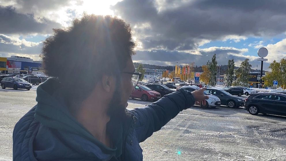 En man som pekar mot en lång kö med bilar i Birsta i Sundsvall.