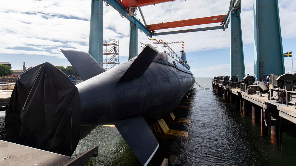 ubåten HMS Gotland under konstruktion vid kaj med stora lyftkranar i bakgrunden.