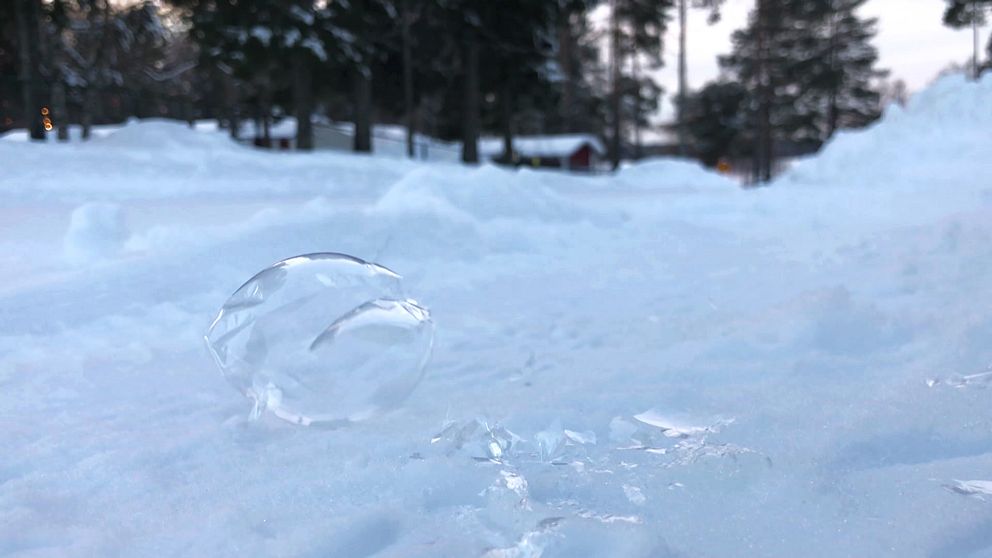 en såpbubbla som frusit till is i luften har landat på den snöiga marken