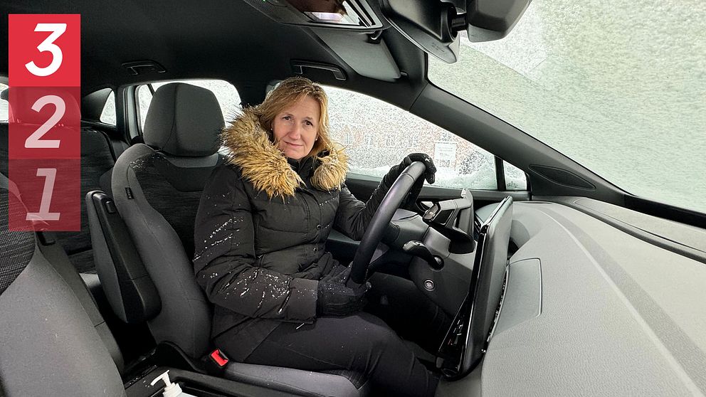kvinna sitter i snöig bil