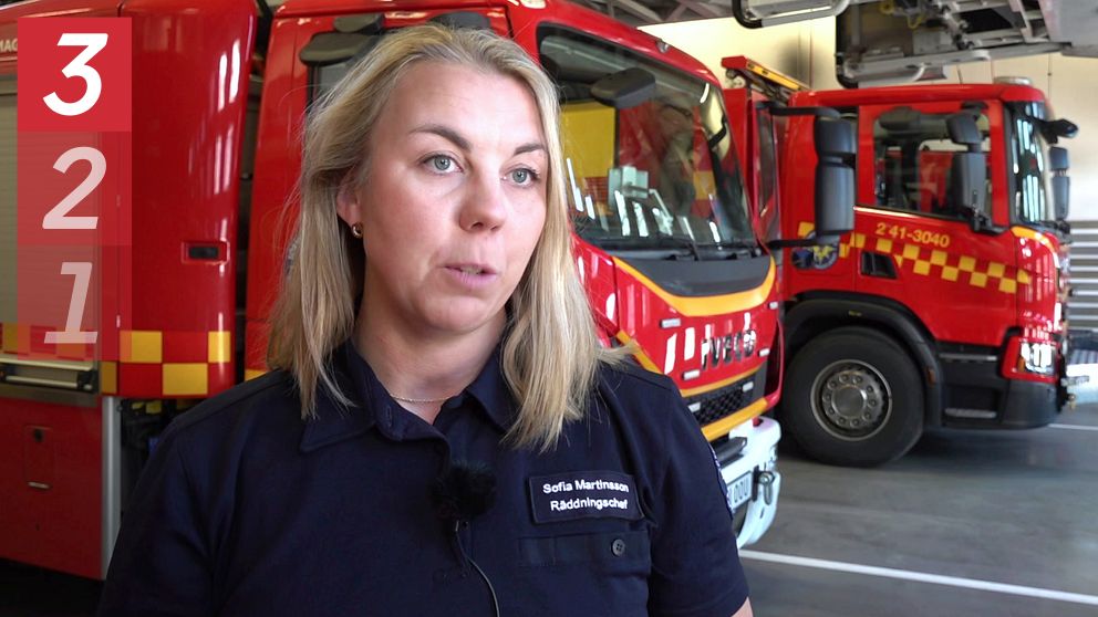 Brandfordon i en brandstation med en person i branduniform framför.